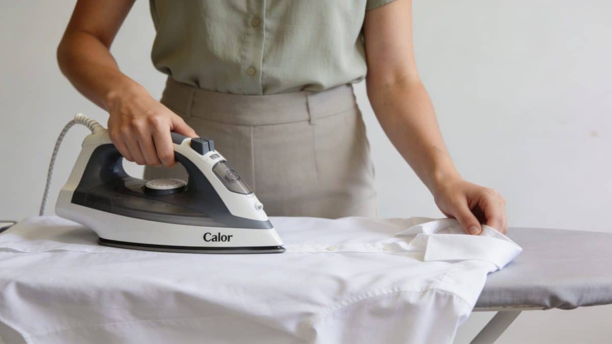 Femme debout repassant chemise blanche avec centrale vapeur moderne Calor