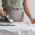 Femme debout repassant chemise blanche avec centrale vapeur moderne Calor