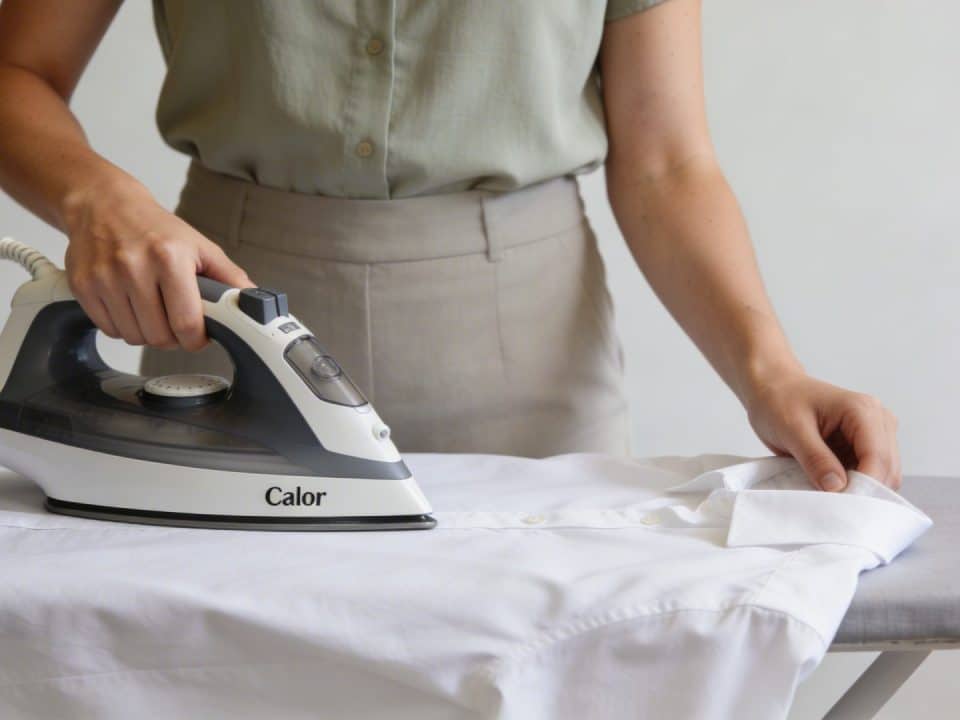 Femme debout repassant chemise blanche avec centrale vapeur moderne Calor