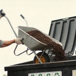 Homme vidant une brouette de terre dans une benne de recyclage