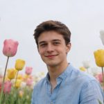 Jeune homme souriant dans un champ de tulipes colorées
