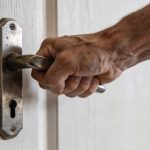 main de bricoleur tirant fort sur une poignee de porte bloquee