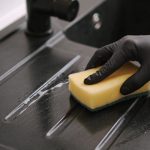 Main noire frottant evier noir en resine avec eponge jaune