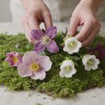 Mains disposant des fleurs fraiches dans la mousse verte sur table