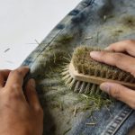Mains frottant un jean tache d herbe avec une brosse