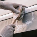 Personne frottant un store banne exterieur avec une brosse et bicarbonate