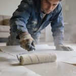 ouvrier penche humidifie des bandes de placo au rouleau dans salon