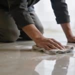 Personne agenouillee frottant un carrelage de sol brillant avec chiffon