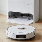 Robot aspirateur Roborock sur parquet clair devant station blanche multifonction