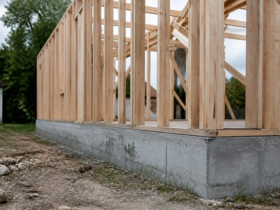 Charpente bois dressée verticalement sur fondation béton grise